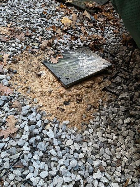 a metal cover on a gravel ground